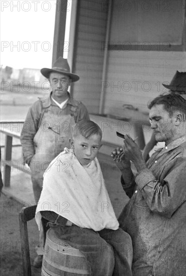 Boy Getting Haircut, Community Barber Shop, Migrant Camp, Kern County, California, USA, Dorothea Lange, Farm Security Administration, November 1936