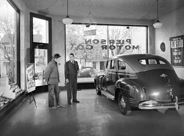 Pierson Motor Company showroom owned by Al Pierson (right) who is showing his one second-hand car to local farmer. Before World War II there always were three brand new cars in his showroom, now during the war, the chief business is repairing, Lititz, Pennsylvania, USA, Marjory Collins, U.S. Office of War Information, November 1942