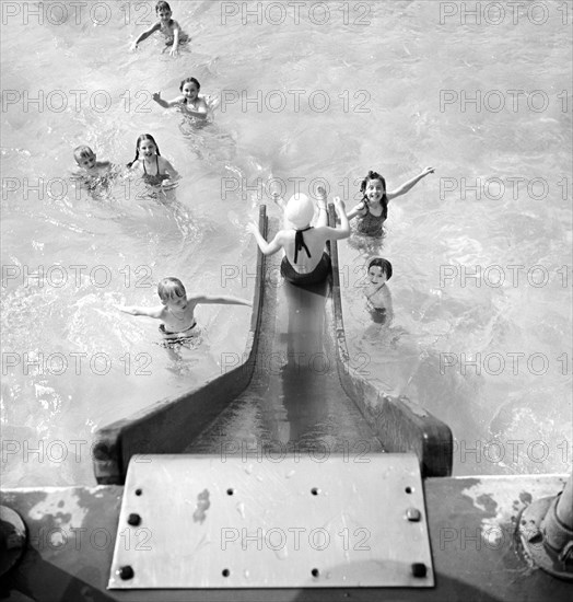 High angle view  of children entering swimming pool from water slide, Greenbelt, Maryland, USA, Marjory Collins, U.S. Office of War Information, June 1942