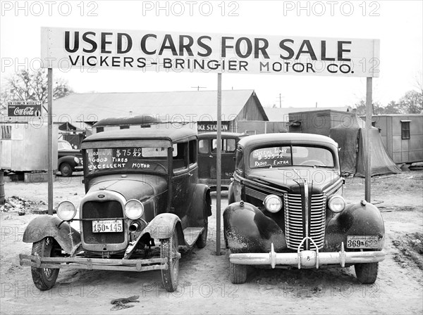 Used cars for sale with signs and prices at service station on main highway near Alexandria, Louisiana, USA, Marion Post Wolcott, U.S. Farm Security Administration, December 1940