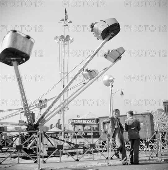 Two teen boys talking near carnival ride, Cotton Carnival, Memphis, Tennessee, USA, Marion Post Wolcott, U.S. Farm Security Administration, May 1940