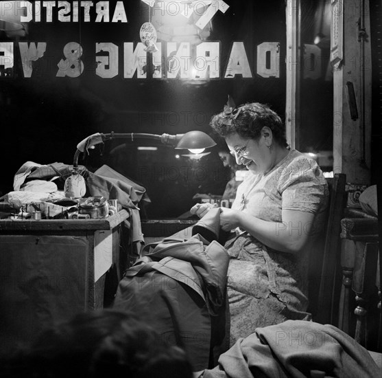 Jewish woman darning clothes in window of darning and weaving shop, Broome Street, New York City, New York, USA, Marjory Collins, U.S. Office of War Information, August 1942