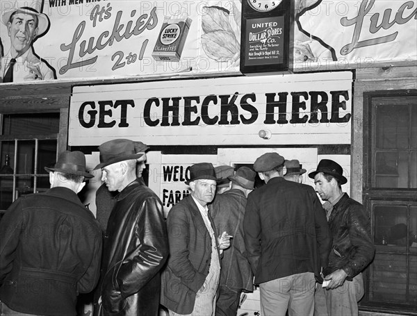 Farmers in warehouse getting their checks after tobacco auction sale, Durham, North Carolina, USA, Marion Post Wolcott, U.S. Farm Security Administration, November 1939