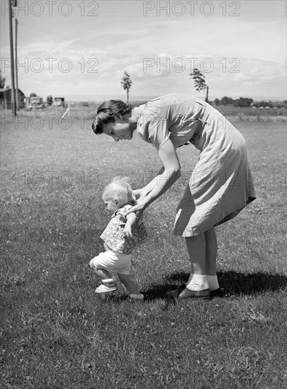 Farm worker's wife teaching her baby girl to walk, FSA (Farm Security Administration) labor camp, Caldwell, Idaho, USA, Russell Lee, U.S. Farm Security Administration, June 1941