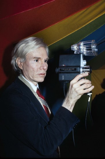 American pop artist Andy Warhol, half-length portrait holding Polaroid Polavision camera, Bernard Gotfryd, 1977