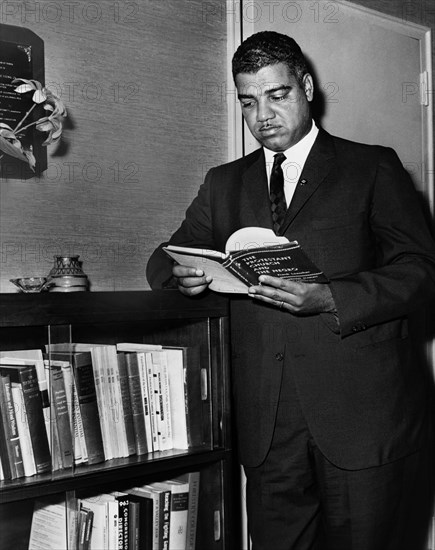 Whitney Young, three-quarter length portrait, standing next to a bookcase, John Bottega, New York World-Telegram and the Sun Newspaper Photograph Collection, 1963