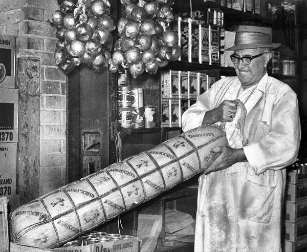 Anthony Nocella lifting a 110-pound provolone cheese at G. Nardella & Sons specialty shop, Brooklyn Terminal Market, Brooklyn, New York City, New York, USA, Roger Higgins, New York World-Telegram and the Sun Newspaper Photograph Collection, 1959