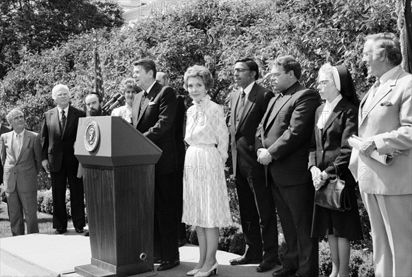 U.S. President Ronald Reagan standing at lectern with U.S. First Lady Nancy Reagan and others during National Day of Prayer ceremony, White House, Washington, D.C., USA, Chick Harrity, U.S. News & World Report Magazine Photograph Collection, May 6, 1982