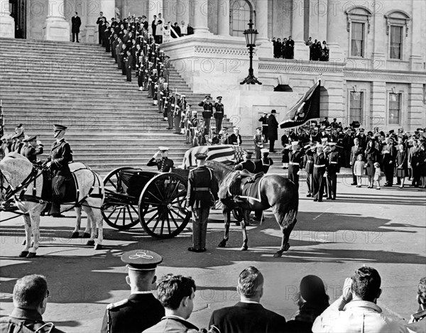 Flag-draped casket of late U.S. President John Kennedy carried by horse-drawn caisson, arriving at U.S. Capitol Building following funeral procession from White House, former U.S. First Lady Jacqueline Kennedy stands at right with her children, Caroline Kennedy and John F. Kennedy, Jr., Washington, D.C., USA, Abbie Rowe, White House Photographs, November 24, 1963