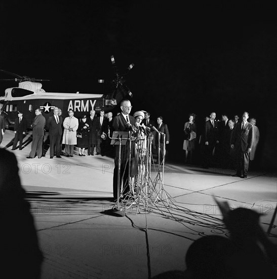 U.S. President Lyndon B. Johnson (at microphones), standing beside First Lady Claudia 'Lady Bird' Johnson, delivering remarks to the nation after taking oath of office aboard Air Force One and arriving at Andrews Air Force Base, Maryland, USA,  Cecil Stoughton, White House Photographs, November 22, 1963