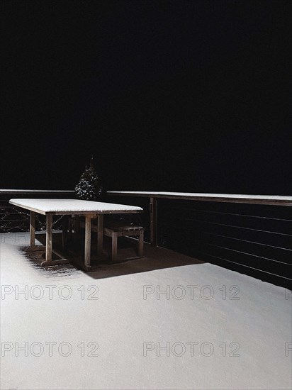 Snow-covered wood table and patio at night