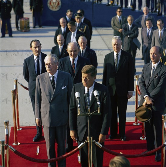 U.S. President John F. Kennedy speaking at arrival ceremonies for British Prime Minister Harold Macmillan (left of Kennedy), l-r immediately behind Kennedy and MacMillan, Sir David Ormsby-Gore, Ambassador of Great Britain; Dean Rusk, Secretary of State; David K. E. Bruce, U.S. Ambassador to Great Britain; Angier Biddle Duke, Chief of Protocol; Andrews Air Force Base, Prince George's County, Maryland, USA, Cecil Stoughton, White House Photographs, April 27, 1962