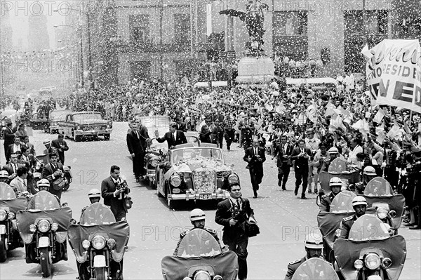 U.S. President John F. Kennedy and Mexican President Adolfo López Mateos waving to crowd from convertible car as confetti falls during motorcade to Los Pinos, the official residence of the President of Mexico, Mexico City, Mexico, Robert Knudsen, White House Photographs, June 29, 1962