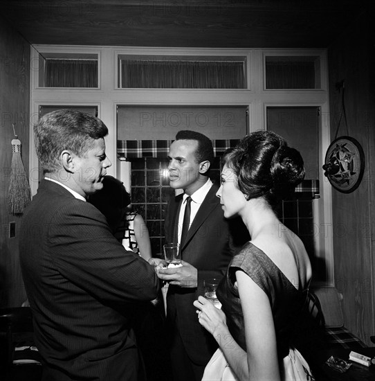 U.S. President John F. Kennedy talking with singer, Harry Belafonte, and Julie Robinson Belafonte during reception at the residence of Arthur B. Krim and Dr. Mathilde Krim, New York City, New York, USA, Cecil Stoughton, White House Photographs,, May 19, 1962