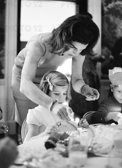 U.S. First Lady Jacqueline Kennedy lighting birthday candle for her daughter, Caroline Kennedy, during joint party for Caroline and John F. Kennedy, Jr., President’s Dining Room, White House, Washington, D.C., USA, Cecil Stoughton, White House Photographs, November 14, 1962