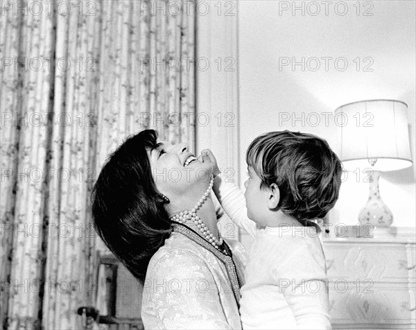 U.S. First Lady Jacqueline Kennedy laughing as her son, John F. Kennedy, Jr., plays with her simulated-pearl necklace in John’s nursery, White House, Washington, D.C., USA, Cecil Stoughton, White House Photographs, November 27, 1962