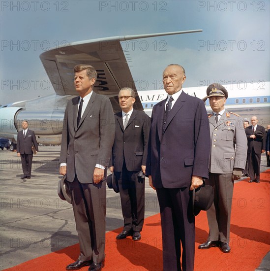 U.S. President John F. Kennedy standing with Chancellor of West Germany, Konrad Adenauer (foreground), and Federal Minister of Defense of West Germany, Kai-Uwe von Hassel; Inspector General of the Bundeswehr, General Friedrich A. Foertsch (immediate background), during his arrival ceremony, Wahn Airport, Bonn, West Germany, Robert Knudsen, White House Photographs, June 23, 1963