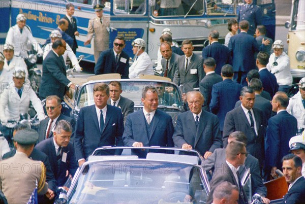 U.S. President John F. Kennedy standing with West Berlin Mayor Willy Brandt and West German Chancellor Konrad Adenauer in open convertible car during his motorcade through West Berlin, West Germany, Cecil Stoughton, White House Photographs, June 26, 1963