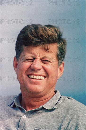 Head and shoulders portrait of squinting and smiling U.S. President John F. Kennedy sitting aboard Presidential yacht, “Honey Fitz,” during Labor Day weekend, Hyannis Port, Massachusetts, USA, Cecil Stoughton, White House Photographs, August 31, 1963