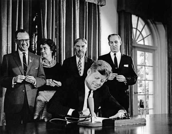 U.S. President John F. Kennedy signing joint resolution in support of Detroit's bid to host 1968 Olympic Games, in background: Michigan Senator Philip A. Hart, Representative Martha W. Griffiths, Representative Neil Staebler, and Representative Harold M. Ryan, Cabinet Room, White House, Washington, D.C., USA, Abbie Rowe, White House Photographs, September 16, 1963