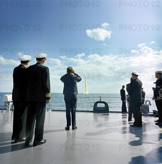 U.S. President John F. Kennedy (rear view, center left) aboard the U.S. Naval ship USS Observation Island watching demonstration of the firing of a Polaris A-2 missile from the submarine USS Andrew Jackson off the coast of Florida, USA,  Robert Knudsen, White House Photographs, November 16, 1963