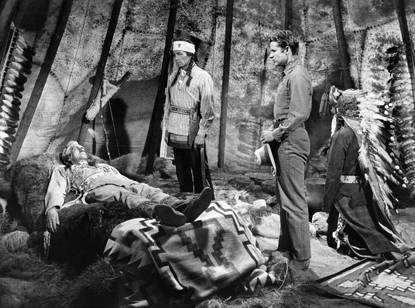 Morris Ankrum (on bed), Audie Murphy (standing right), on-set of the western film, "Drums Across The River", Universal Pictures, 1954