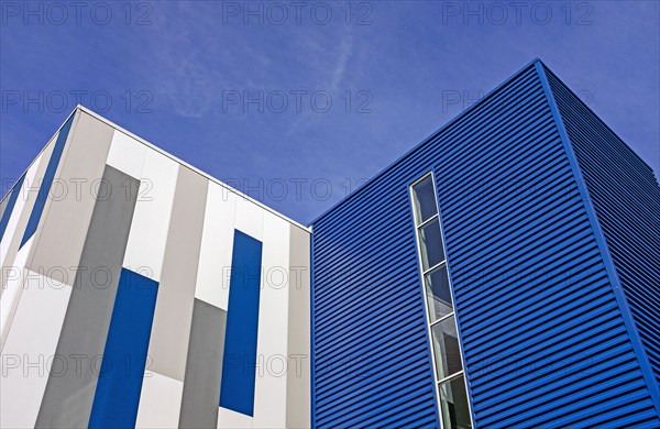 Low angle view of geometric building exterior, against blue sky