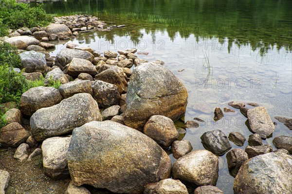 Large rocks at edge of clear lake, Acadia National Park, Maine, USA