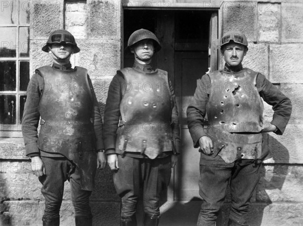 Three U.S. military personnel exhibiting effect of pistol, rifle and machine gun fire on heavyweight body armor, a result of testing conducted by the Army Ordnance Department, Fort de la Peigney, Langres, France, U.S. Army Signal Corps, 1918