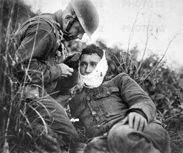 U.S. soldier of Company K, 110th Regiment Infantry (formerly 3rd and 10th Infantry, Pennsylvania National Guard), just wounded, receiving first-aid treatment from a comrade, Varennes-en-Argonne, France, U.S. Army Signal Corps, September 26, 1918