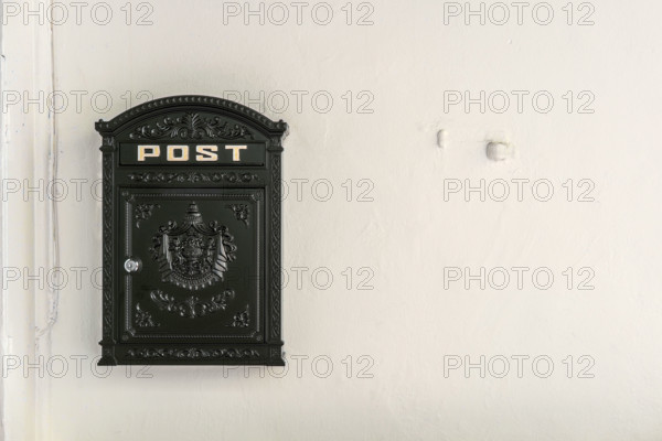 Black metal mailbox on white wall