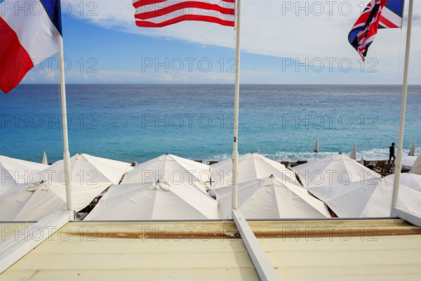 Beach umbrellas and Franch, American and British flags at beach club on Mediterranean Sea, Nice, Flag