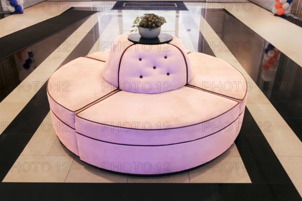 Pink circular couch on marble floor in hotel lobby