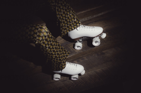 Woman wearing white roller skates and flaired pants with a geometric pattern