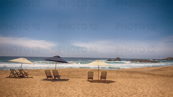 Beach chairs and sun umbrellas on sandy beach, Mexico