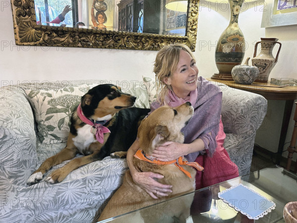 Smiling woman with her two dogs on sofa