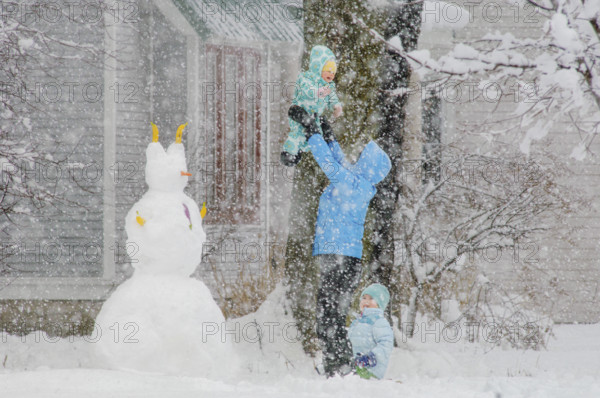 Mother playing with her two children in snow