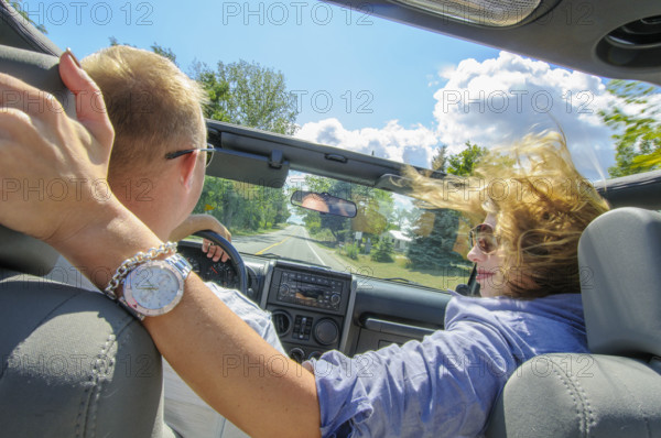 Rear view of couple riding in car with open sunroof on sunny day