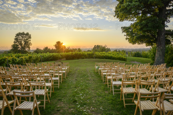 Rows of wood folding chairs set up for outdoor event at sunset