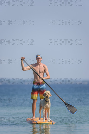 Teen boy with pet golden doodle on paddle board