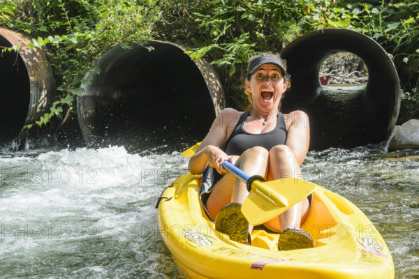 Mid-adult woman kayaking through a culvert