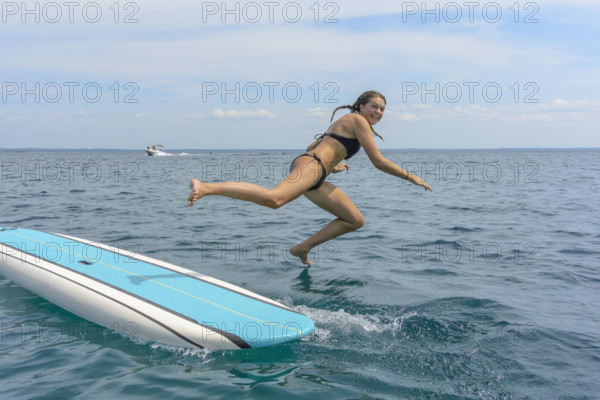 Young adult woman jumping off paddle board