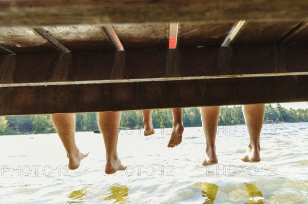 Family with dangling feet sitting on dock