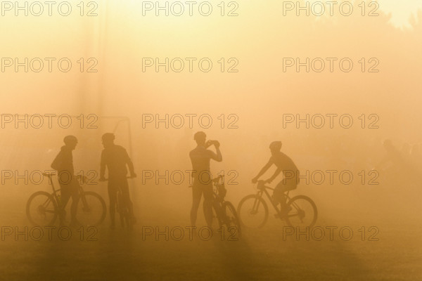 Silhouette of four cyclists waiting in fog for start of bike race