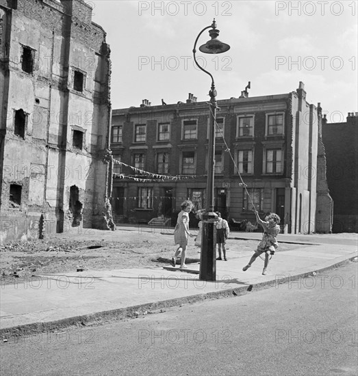 Children swinging on a lamppost, London, 1960-1965