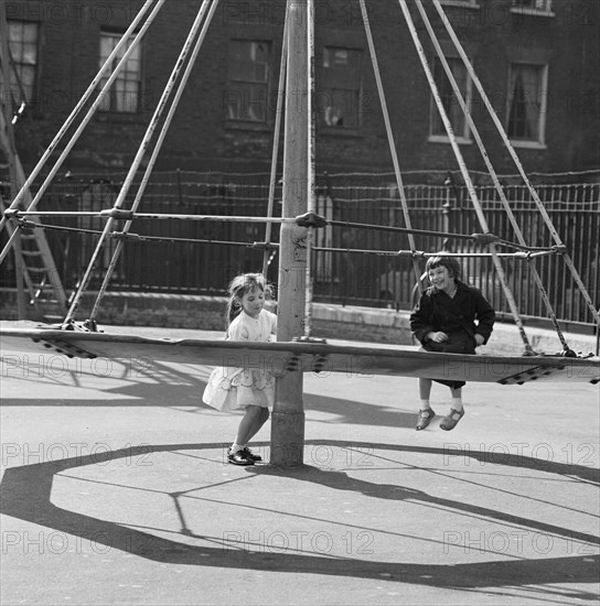 Girls playing on a 'witch's hat' in a playground, London, 1960-1965