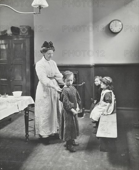 Nurse examining children before 'cleansing', Chaucer Cleansing Station, London, 1911. Artist: Unknown.