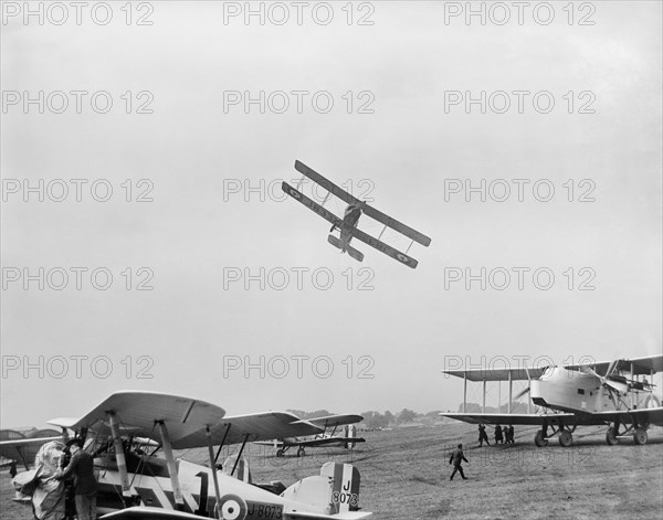 Avro 504 biplane flying very low over parked aircraft at the RAF Pageant, Hendon, London, 1927