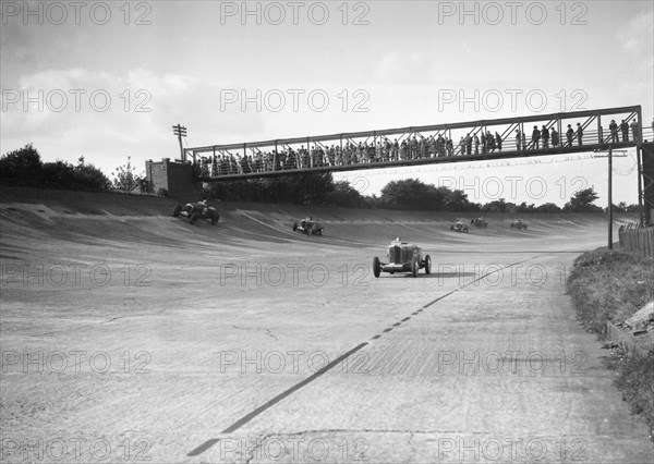 Cars racing on Byfleet Banking during the BRDC 500 Mile Race, Brooklands, 3 October 1931. Artist: Bill Brunell.