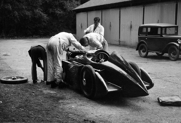 Mechanics working on Leon Cushman's Austin 7 racer for a speed record attempt, Brooklands, 1931. Artist: Bill Brunell.